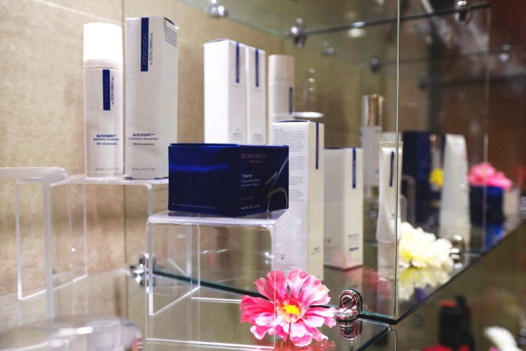 Cosmetic ZO products displayed in glass case with flowers
